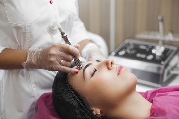 Mesotherapy. Young doctor making face lifting apparatus procedure. Dermatologist doing meso.