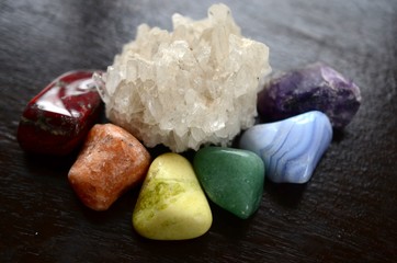 Bright colored rainbow crystal layout. Healing crystal of all colors, variety of stones. Colorful healing crystals, on wood background. Hand holding crystals, healing reiki chakra gemstones. 