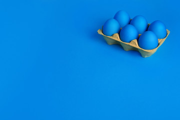 Six blue painted Easter eggs in yellow wrapping on blue background. Happy Easter holiday card or banner. Copy space.
