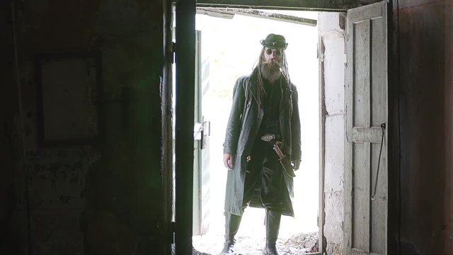 A tough guy in a black raincoat opens the door to an abandoned room with a kick. The room lights up. Slow motion.
