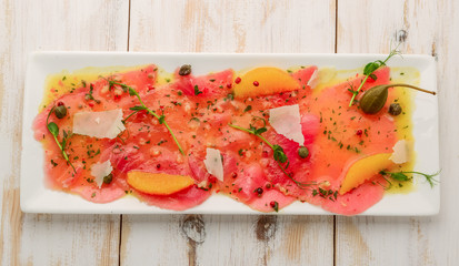 Restaurant Starter Menu with Slightly Salted Salmon Fillet Isolated on White Background. Thin Slices of Red Fish or Trout with Lemon and Greens o