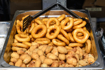 Large group of freshly fried calamari rings and mussels on  display for sale at a street food festival, ready to eat seafood 