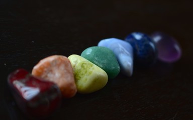 Rainbow Healing Crystals on wood table. Natural lighting with macro lens, rainbow stones. Red Jasper, Orange Calcite, Serpentine, Green Quartz, Blue Lace Agate, Sodalite, Amethyst. 