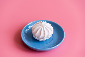 Marshmallow in a blue plate on a pink background. copy space