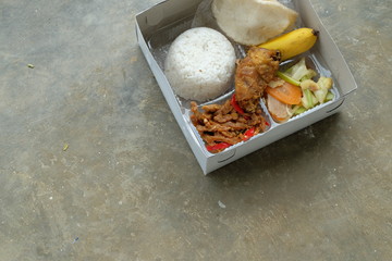 Fototapeta na wymiar Nasi kotak or lunch box. Mixed rice with vegetable and chicken fillet.