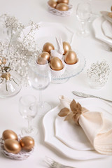 Obraz na płótnie Canvas Happy Easter! Golden decor and table setting of the Easter table with white dishes of white color.