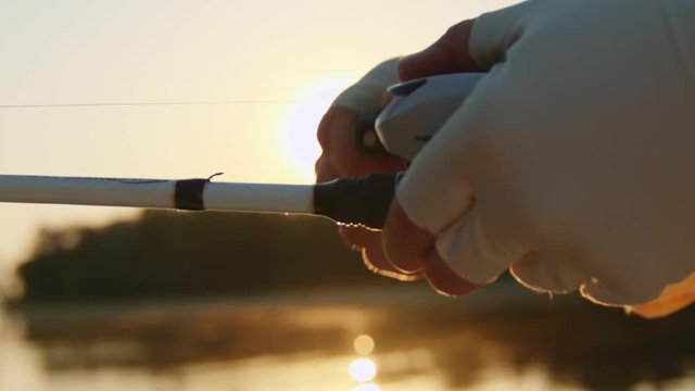 Fisherman Reels in Fish During Sunset - Closeup