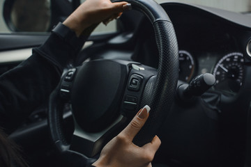 Women's hands on the wheel of a car while driving