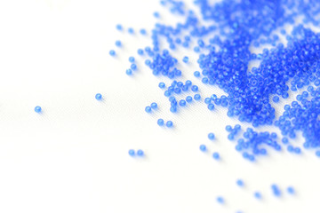 Transparent seed beads dark blue color on a textile background close up