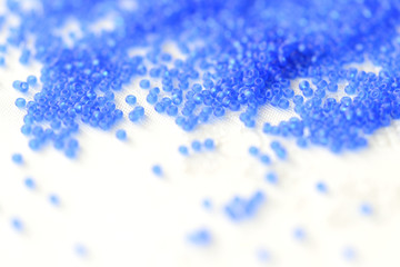 Transparent seed beads dark blue color on a textile background close up
