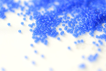 Transparent seed beads dark blue color on a textile background close up