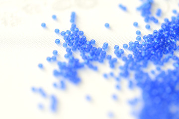 Transparent seed beads dark blue color on a textile background close up