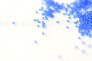 Transparent seed beads dark blue color on a textile background close up