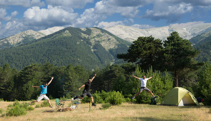 Fototapeta na wymiar Friends jumping into air in a camping ground.g