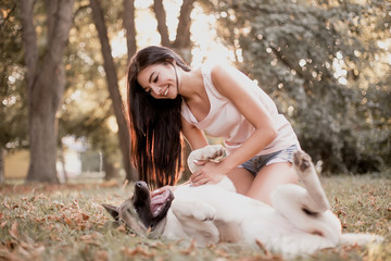 Beautiful woman playing with a dog walking in the park.