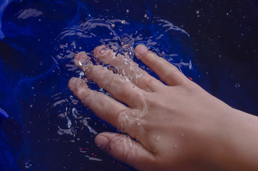 Fototapeta premium Children's hands against the background of water and white.
