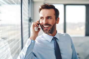 Handsome businessman talking on phone in modern office