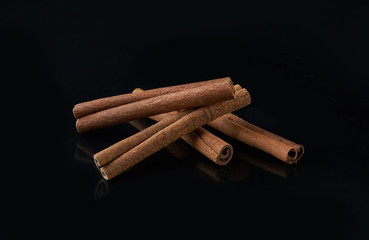 cinnamon sticks on black background with reflection