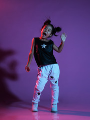Asian kid girl in shirt and pants with stars and white sneakers greets and shouts joyfully