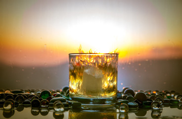 A Glass Of whiskey with ice and gold sunlight. Outdoor shot of whiskey with splash on sunset...