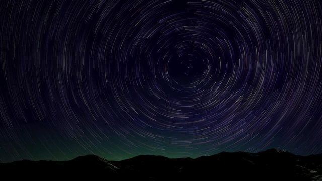 Star Trails Spinning Around Polaris with Mountain Range and Green Glow in Night Sky - 3D Animation.
