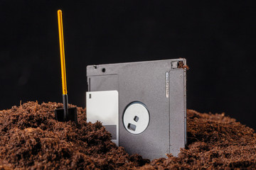 The diskette is half buried in the ground, next to a shovel