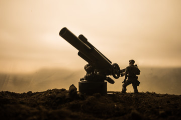 Battle scene. Silhouette of old field gun standing at field ready to fire. With colorful dark foggy...