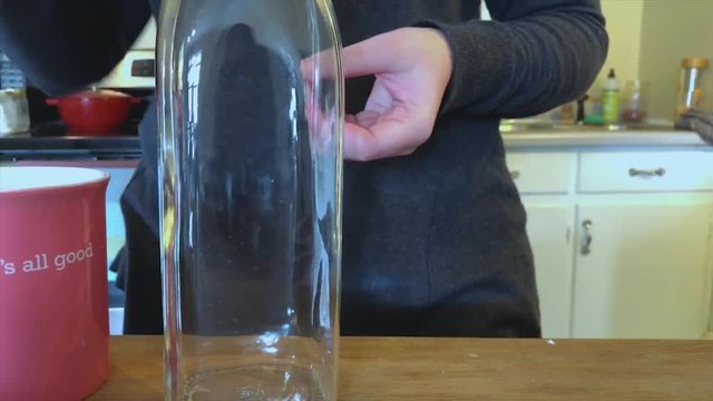 Woman pouring handmade organic pink soda into tall glass bottle part two