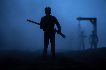 Man with riffle against zombie attack. Zombie apocalypse. Scary view of blurred zombies at cemetery and spooky cloudy sky with fog.