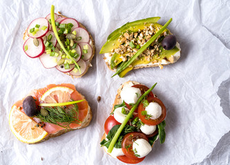 Sandwiches or tapas prepared with cream cheese , vegetables and salmon, over white paper background. Healthy food for lunch or breakfast. Flat lay.
