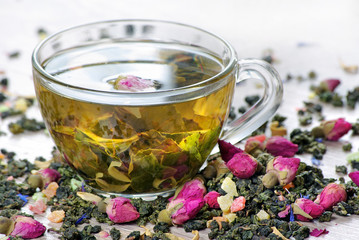 green tea. cup of green tea with flowers and fruit pieces close up. blend tea