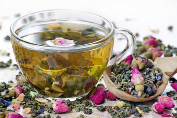 green tea. cup of green tea with flowers and fruit pieces close up. blend tea