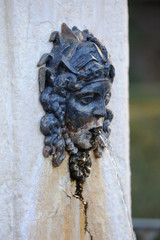 cara clásica de metal en fuente echando agua