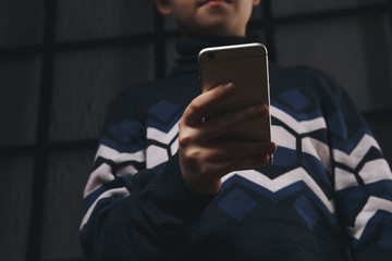 Teen boy holding phone and feeling sad. Victim of cyberbullying. Phone bullying