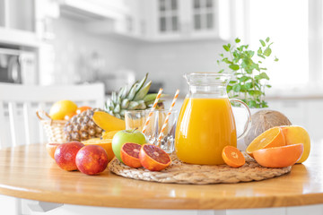 Multifruit juice and fresh fruit on table on kitchen background closeup
