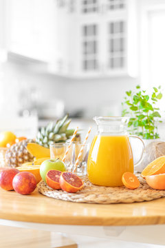 Multifruit juice and fresh fruit on table on kitchen background closeup