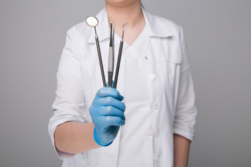 Female dentist with tools on grey background
