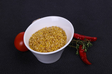 Raw bulgur in the bowl with tomatoes and garlic