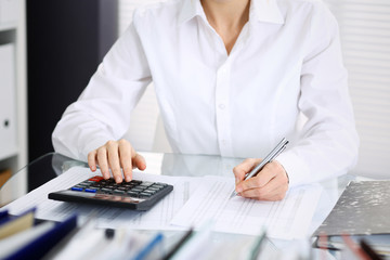Unknown bookkeeper woman or financial inspector  making report, calculating or checking balance, close-up. Business portrait. Audit or tax concepts