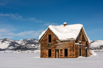 Old weathered and abandoned homestead with a Christmas wreath over the door