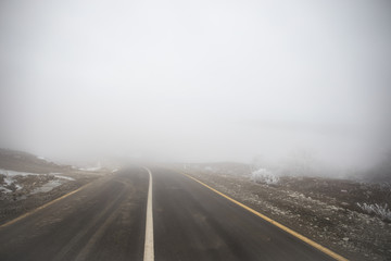 Landscape with beautiful fog in forest on hill or Trail through a mysterious winter forest with autumn leaves on the ground. Road through a winter forest. Magical atmosphere.