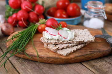 crispbread with quark and fresh chive, radish and tomatoes on a rustic wooden table - healthy breakfast with fresh herbs 