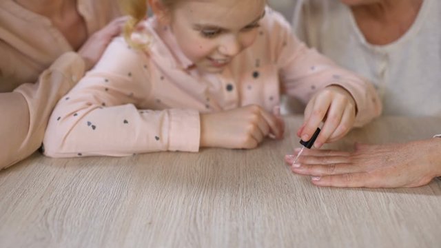 Little girl painting grandmother nails doing manicure, female beauty, leisure