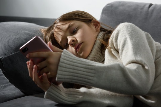 The young girl is looking at the screen of a smartphone.