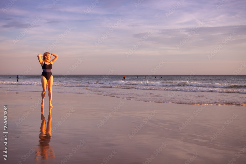 Wall mural beauty girl in a swimsuit on the coastline posing in the evening light