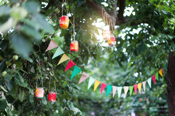 Garland of colorful flags and homemade flashlights at sunset in summer garden. Concept of...