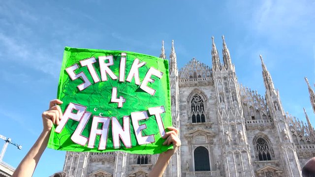 Picket sign for global strike for climate day, Duomo building, cathedral square, Milan, Italy. Friday for future, Greta Thunberg ecological movement, placard environmental activism "STRIKE 4 PLANET"