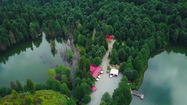 4K drone dolly sideways shot, in slow motion, houses between pond and lake, over beautiful Lake Karagol, reflecting trees and sky, in Borcka District, Artvin Province, Turkey