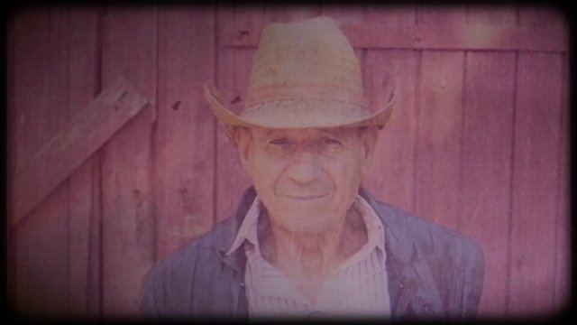 Old farmer in a straw hat near the farm. Portrait of an elderly man. Retiree. Video archive. Retro. Vintage. Farm animals. Raising animals for meat. Agriculture. Organic food. Ranch