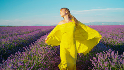 Woman in yellow dress walking through lavender field